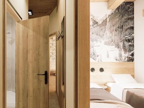 A wooden door leading to a room with a bed and a large window with a snowy mountain view. - Beautiful penthouse in the center of Westendorf. (Westendorf)