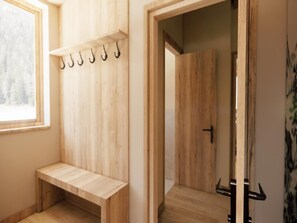 A wooden locker room with a bench, hooks, and a door leading to another room. - Beautiful penthouse in the center of Westendorf. (Westendorf)