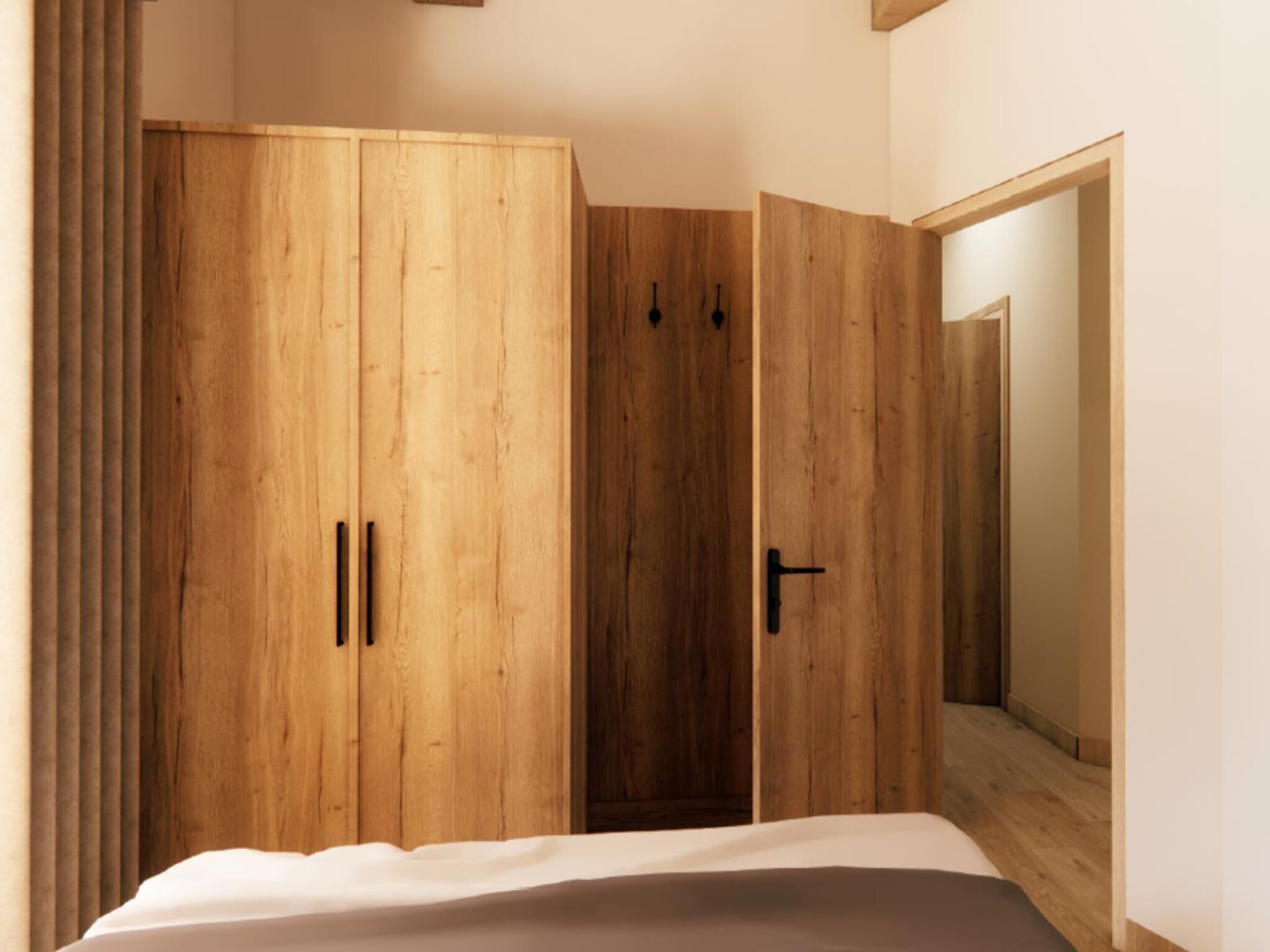 A bedroom with a wooden wardrobe, a bed, and a door leading to another room.