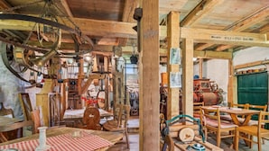 Een rustiek interieur met houten meubels, een tafel met een geruit tafelkleed en diverse antieke objecten.