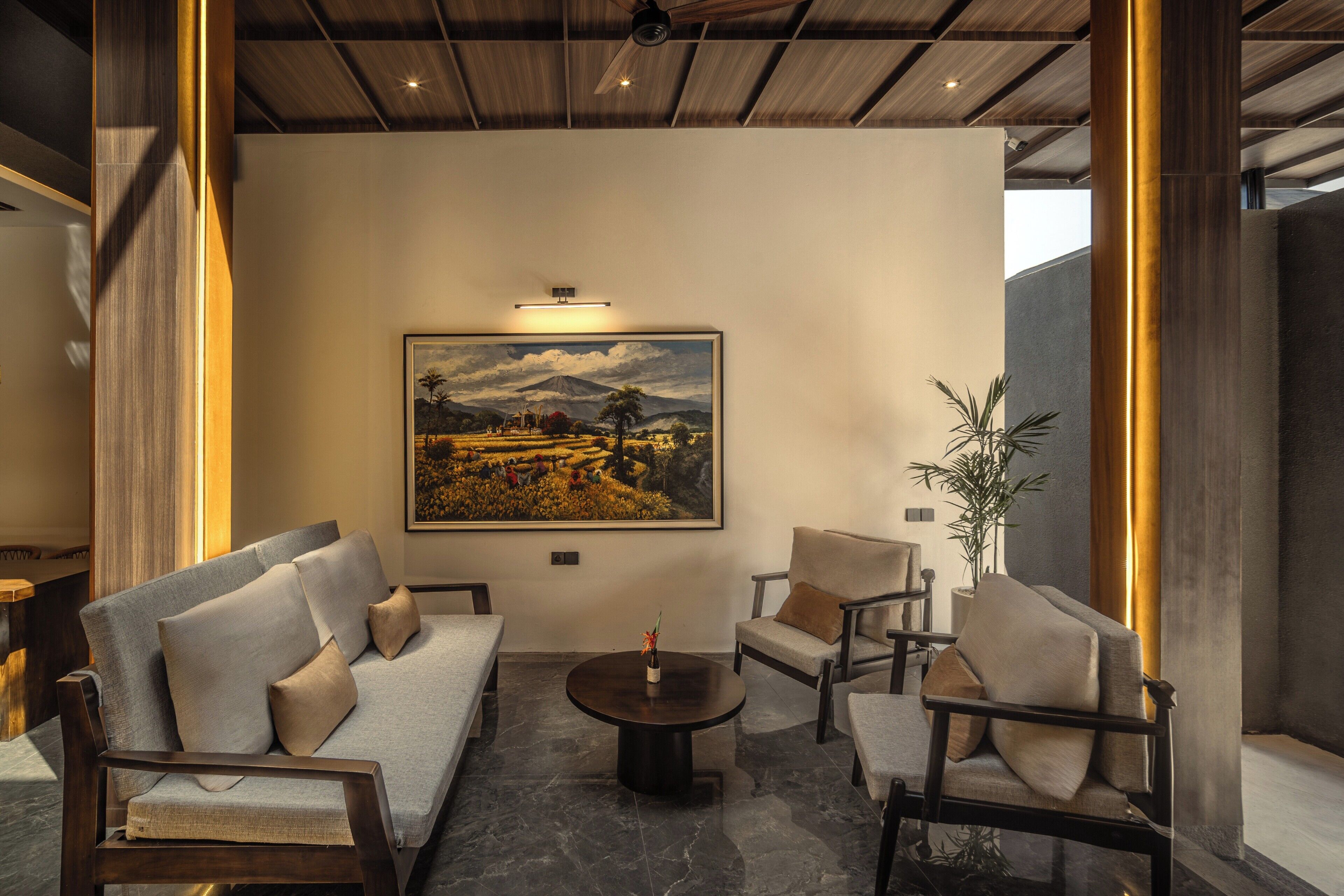 Un interior moderno con un conjunto de sofás, sillones, una mesa de centro y un cuadro de paisaje grande en la pared.