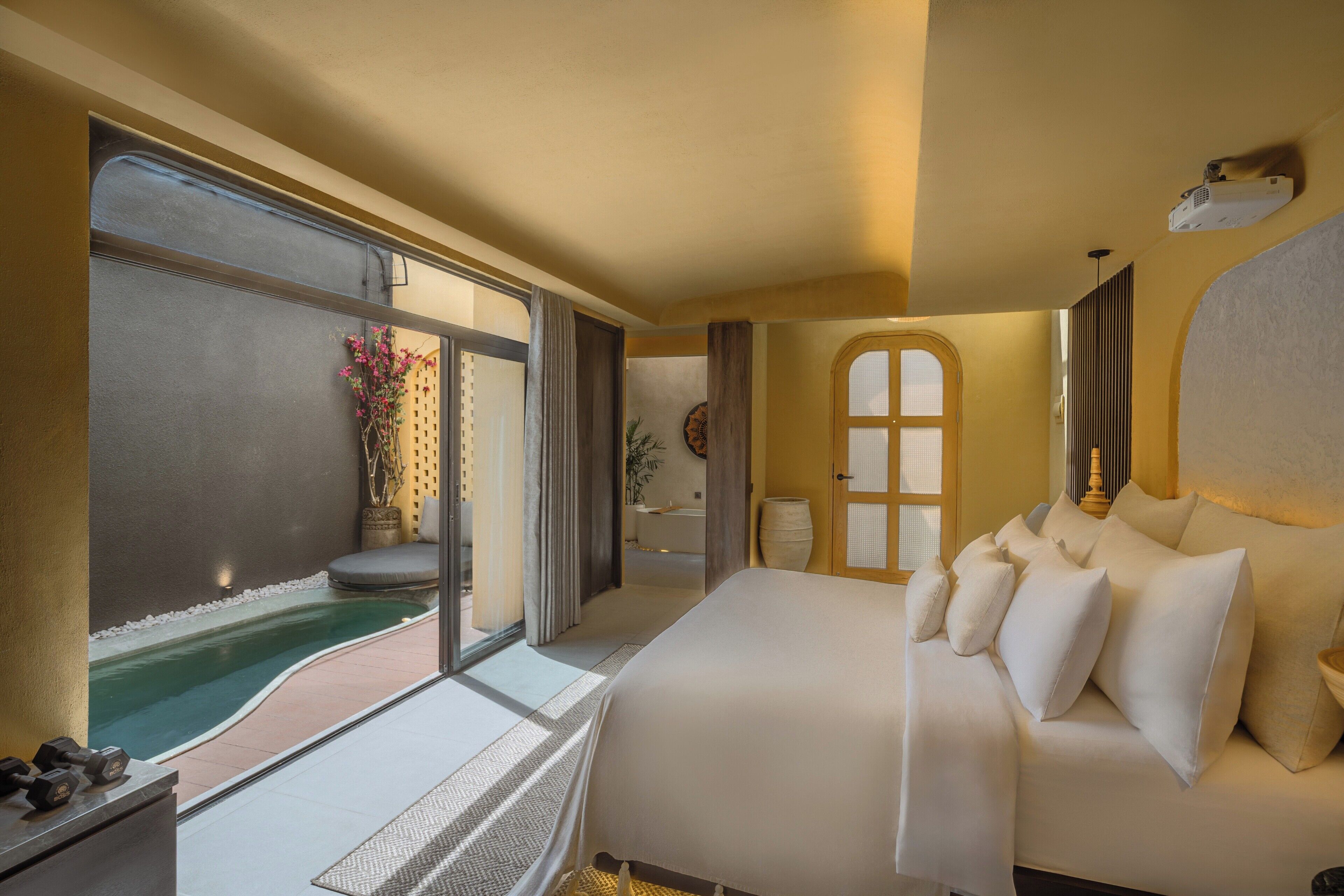 Habitación de hotel con una cama grande, una piscina pequeña y vistas al exterior.