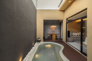 A modern interior with a small water feature, a dining area, and a seating area with a sofa and cushions. - Leedon Villa Seminyak by Ini Vie Hospitality (Kuta Utara, Badung)