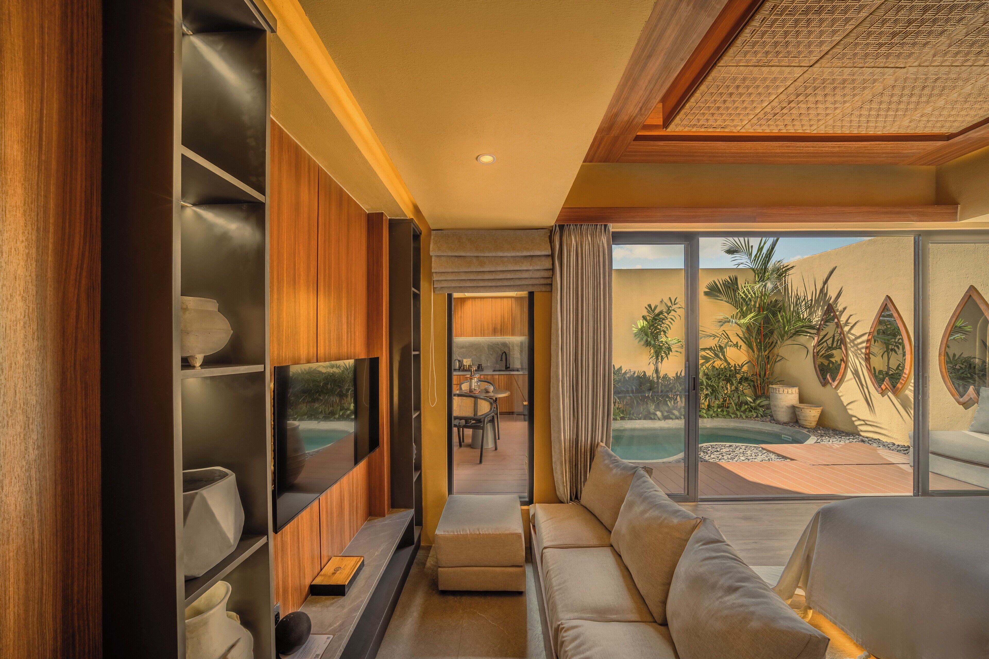 Un interior moderno con un sofá, una zona de comedor y vistas a una piscina.