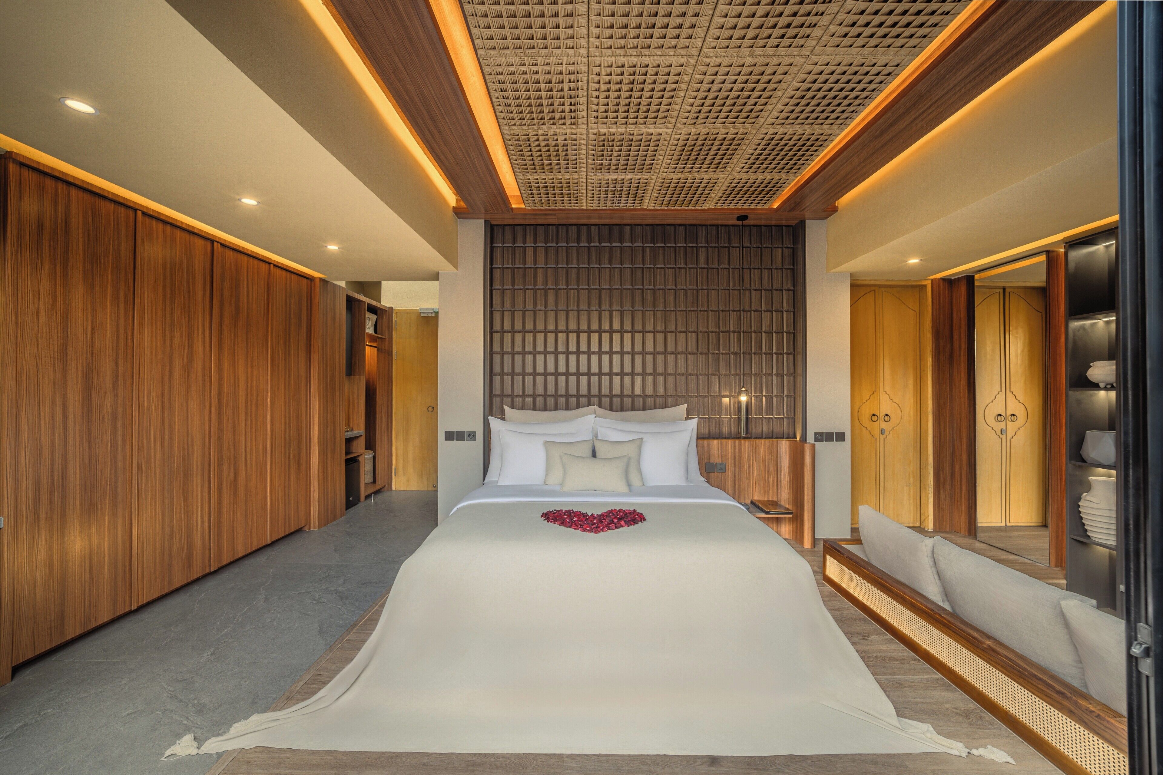 Habitación de hotel con una cama grande, paneles de madera y un diseño de techo moderno.