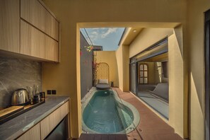 Corredor estreito que dá para uma piscina, com uma área de cozinha de um lado e um espaço de estar do outro.