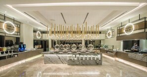 Eine moderne Hotelhalle mit einem Marmor-Rezeptionsschalter, einer Kaffeemaschine und einem Koch, der Speisen zubereitet.