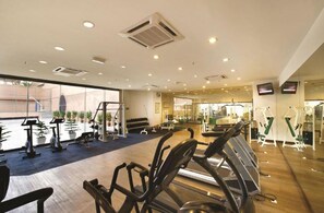 Ein Fitnessstudio mit unterschiedlichen Trainingsgeräten, großen Fenstern und Holzboden.