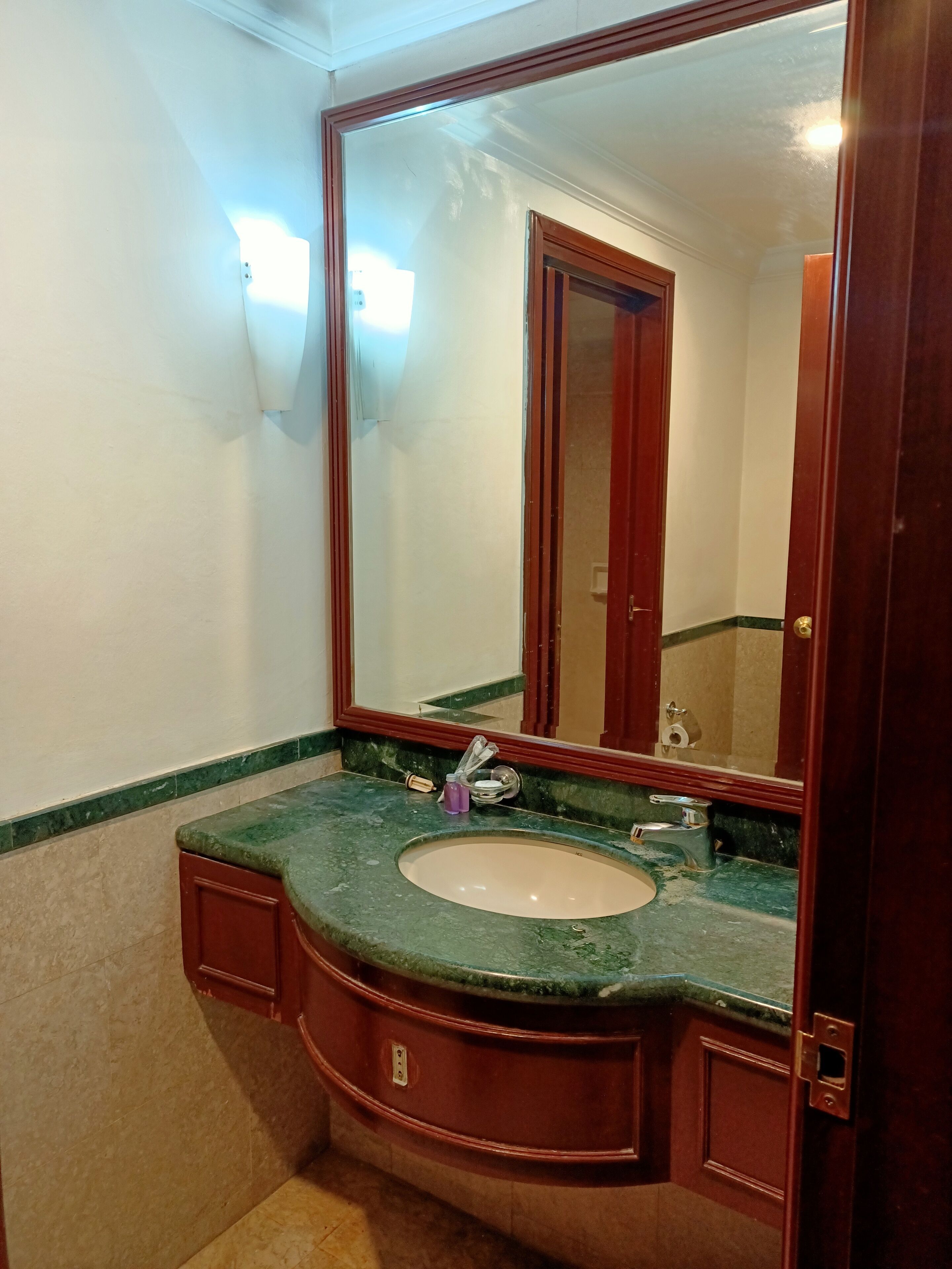 A bathroom with a marble sink, a large mirror, and a wooden vanity.