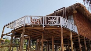 A wooden structure with a thatched roof, a white railing, and a wooden deck. - Meghsomudro Eco Resort Sajek (Sajek)