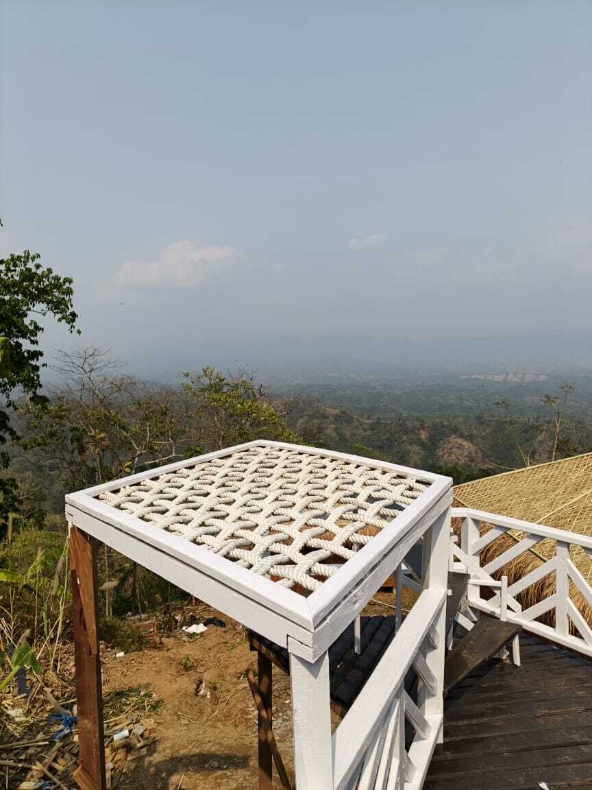 Un espacio exterior con asientos blancos, una mesa de mimbre y una terraza de madera.