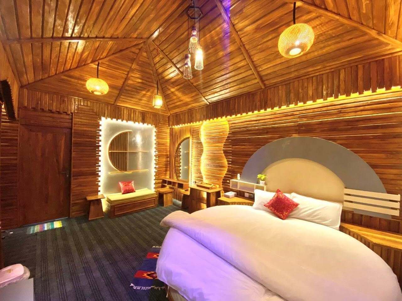A wooden-themed bedroom with a large bed, bedside tables, and a mirror.