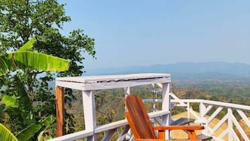 A wooden deck with a white railing, a rocking chair, and a small table.