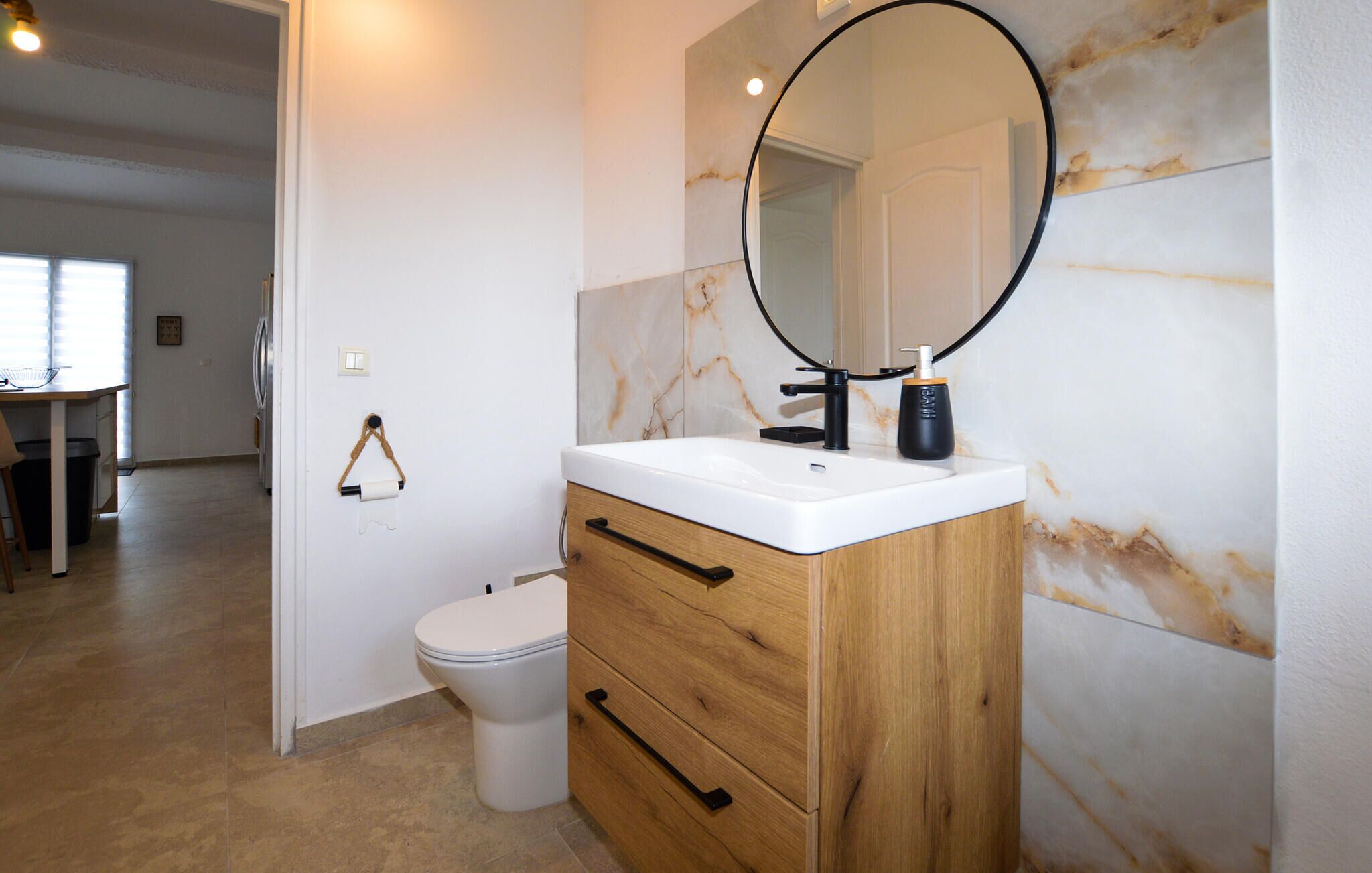 Een badkamer met toilet, een wastafel met spiegel en een marmeren wand.