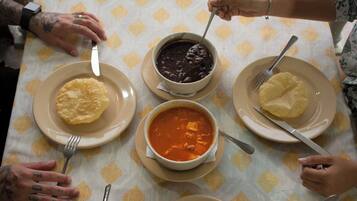 A group of people dining around a table with plates of food, forks, and a watch on someone's wrist.