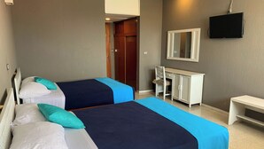 A hotel room with two beds, a desk, a chair, a television, and a wardrobe.