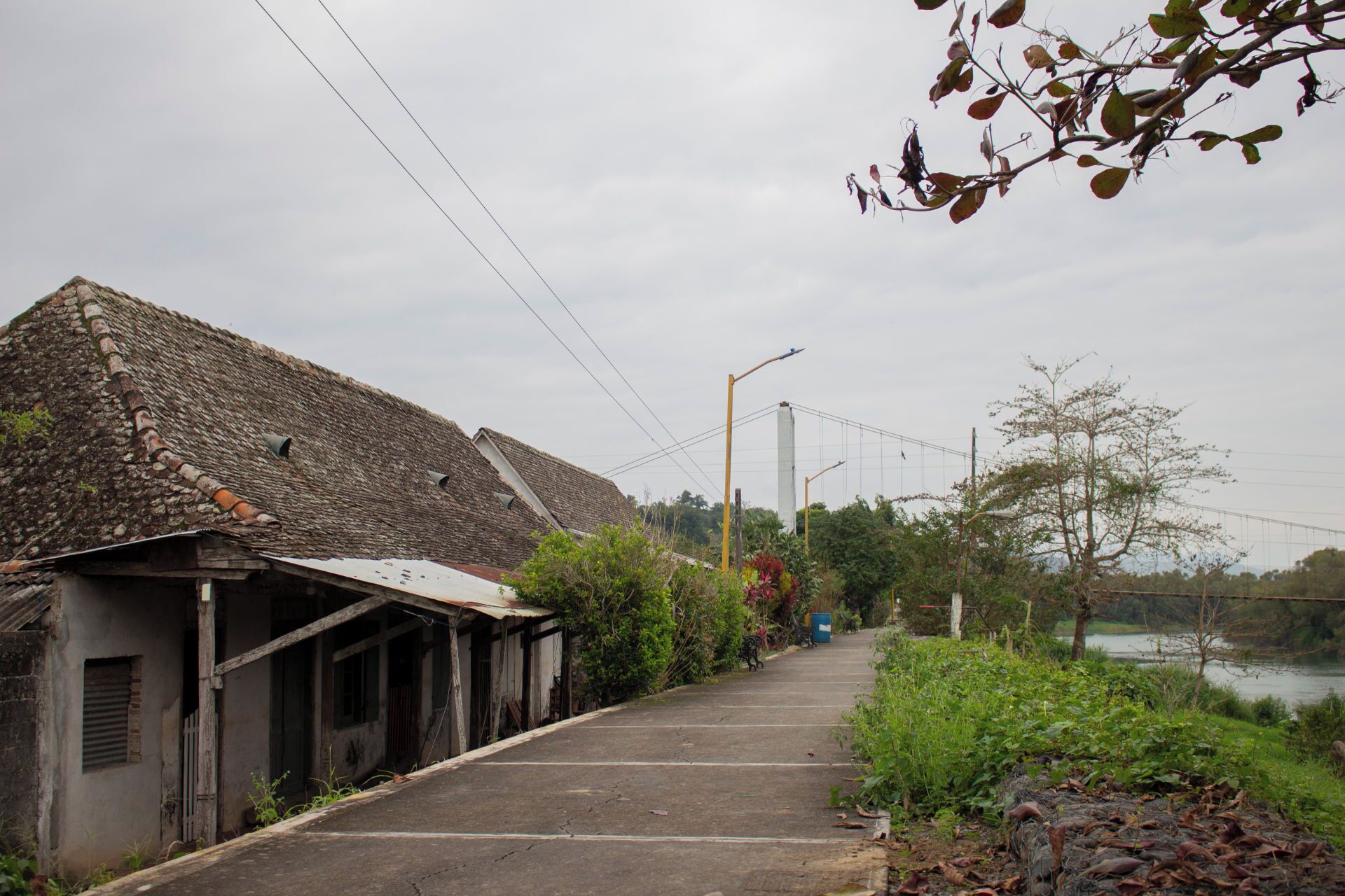 Una calle tranquila con una hilera de edificios antiguos, cielo despejado y una masa de agua al fondo.