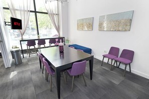 A modern meeting room with a large table, purple chairs, a blue sofa, and artwork on the walls. - Stylish 2BR Escape - 10 minutes walk to RiverWalk (Milwaukee)