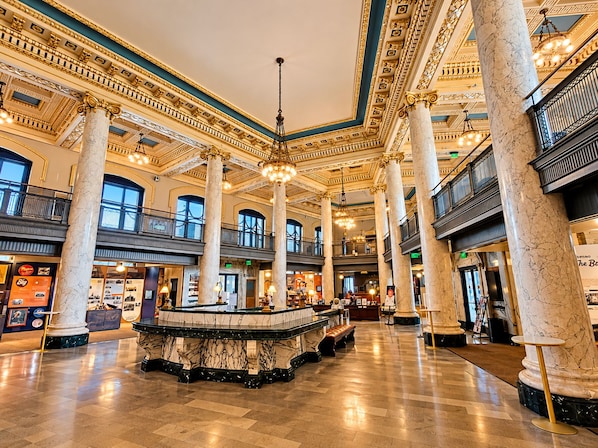 A spacious lobby with marble columns, a central fountain, and a mezzanine level with balconies.