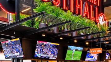 A bar area with neon signage, multiple screens, and seating.
