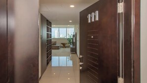 A hallway leading to a living area with a large window, a sofa, and a coffee table. - Corporate Stays Miami (Asunción)