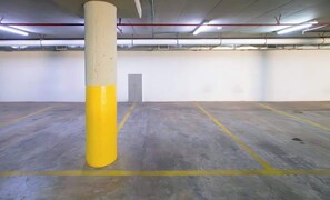 An empty parking garage with concrete floors and yellow lines, a pillar, and a door. - Corporate Stays Miami (Asunción)