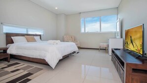 A modern bedroom with a large bed, a chair, a TV, and a window. - Corporate Stays Miami (Asunción)