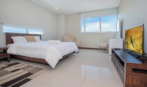 A modern bedroom with a large bed, a chair, a TV, and a window. - Corporate Stays Miami (Asunción)
