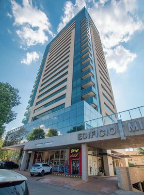 A tall, modern building with a glass facade and a sign reading 'EDIFICIO MI'. - Corporate Stays Miami (Asunción)