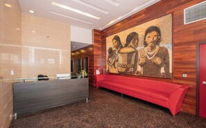A reception area with a wooden wall, a red bench, and a large abstract painting. - Corporate Stays Miami (Asunción)