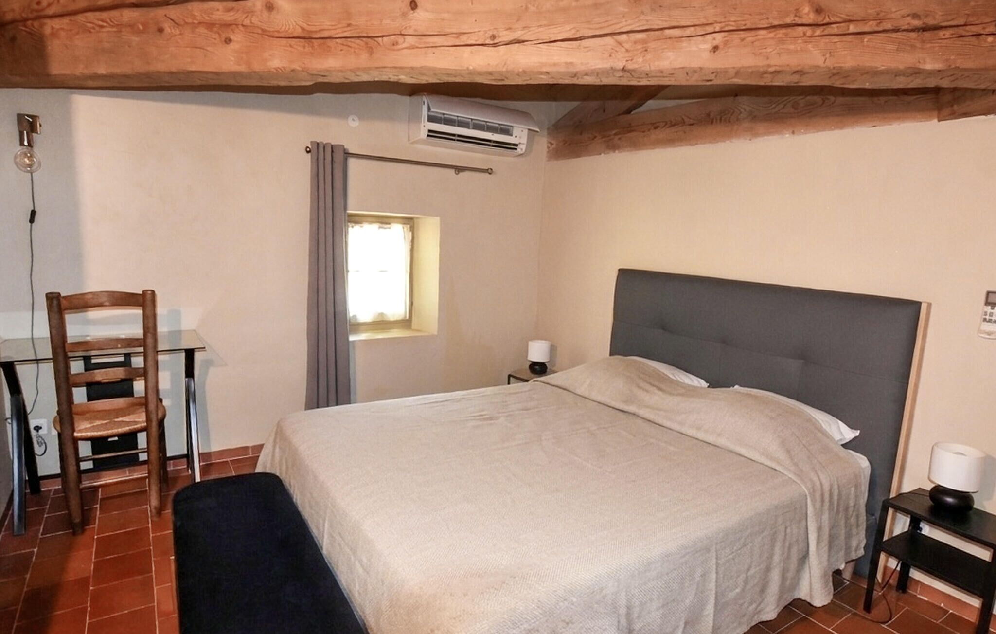 A bedroom with a bed, a chair, a desk, and a window.