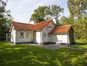 A white building with a red-tiled roof, labeled 'Dunenkov,' featuring a covered porch and a paved entrance area. - Bungalow Near Dishoek Beach (Koudekerke)