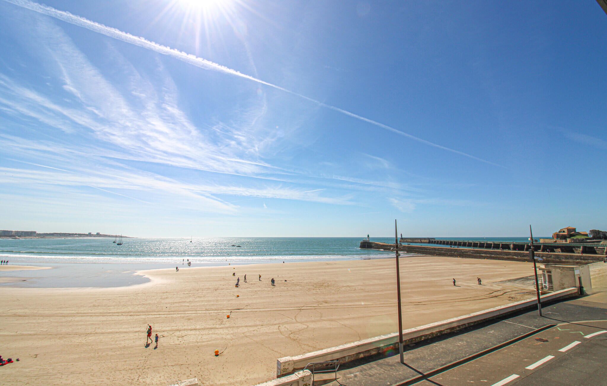 Une plage avec une jetée, un ciel dégagé et une mer calme.