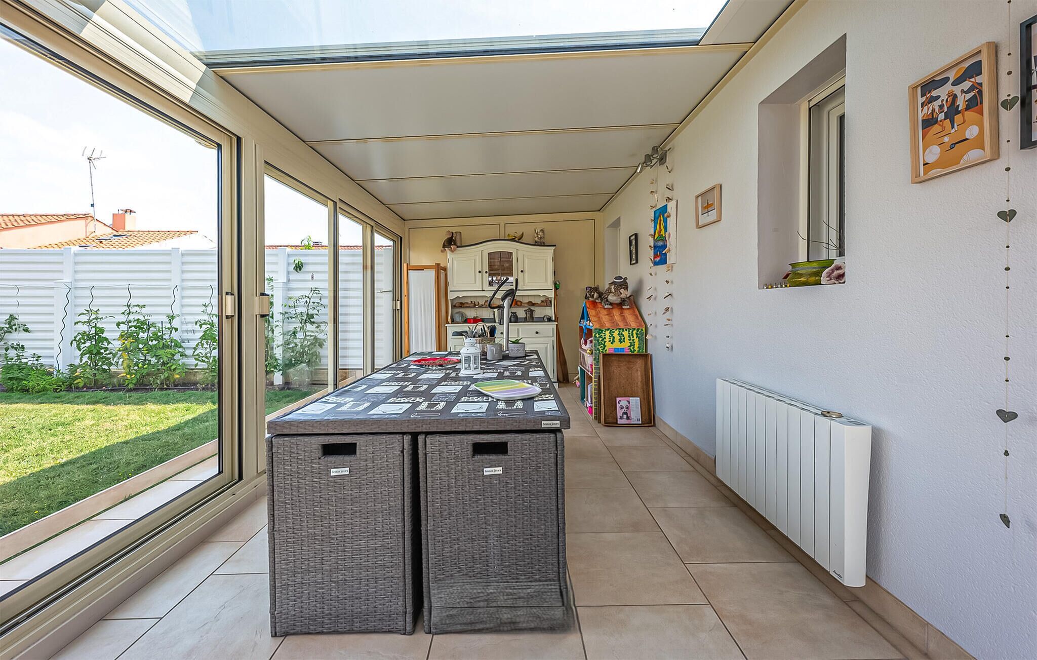 A sunlit kitchen with a large island, white cabinets, and a view of the garden.