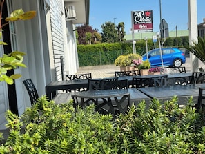 An outdoor seating area with tables and chairs, a blue car parked nearby, and a sign for 'La Stella' restaurant. - Locanda patoea  (Borgoricco)