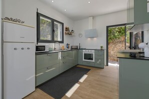 A modern kitchen with a refrigerator, microwave, oven, and sink. - Casa Zoe 6 pax - Pedreguer, Costa Blanca (Pedreguer)