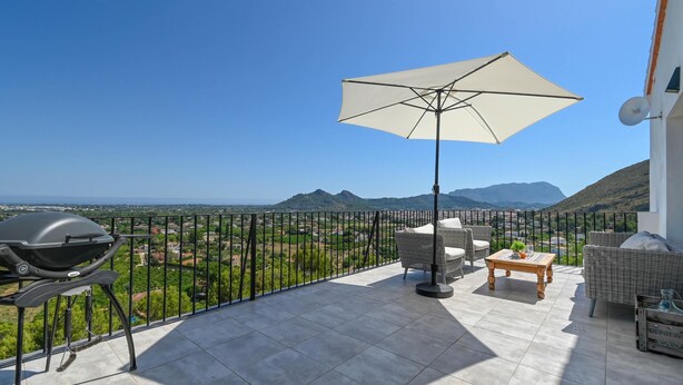 Ein Balkon mit Grill, Gartenmöbeln und Blick auf die Landschaft.