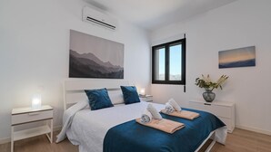 Ein modernes Schlafzimmer mit einem Bett, Nachttischen, einem Fenster und Kunstwerken an den Wänden.