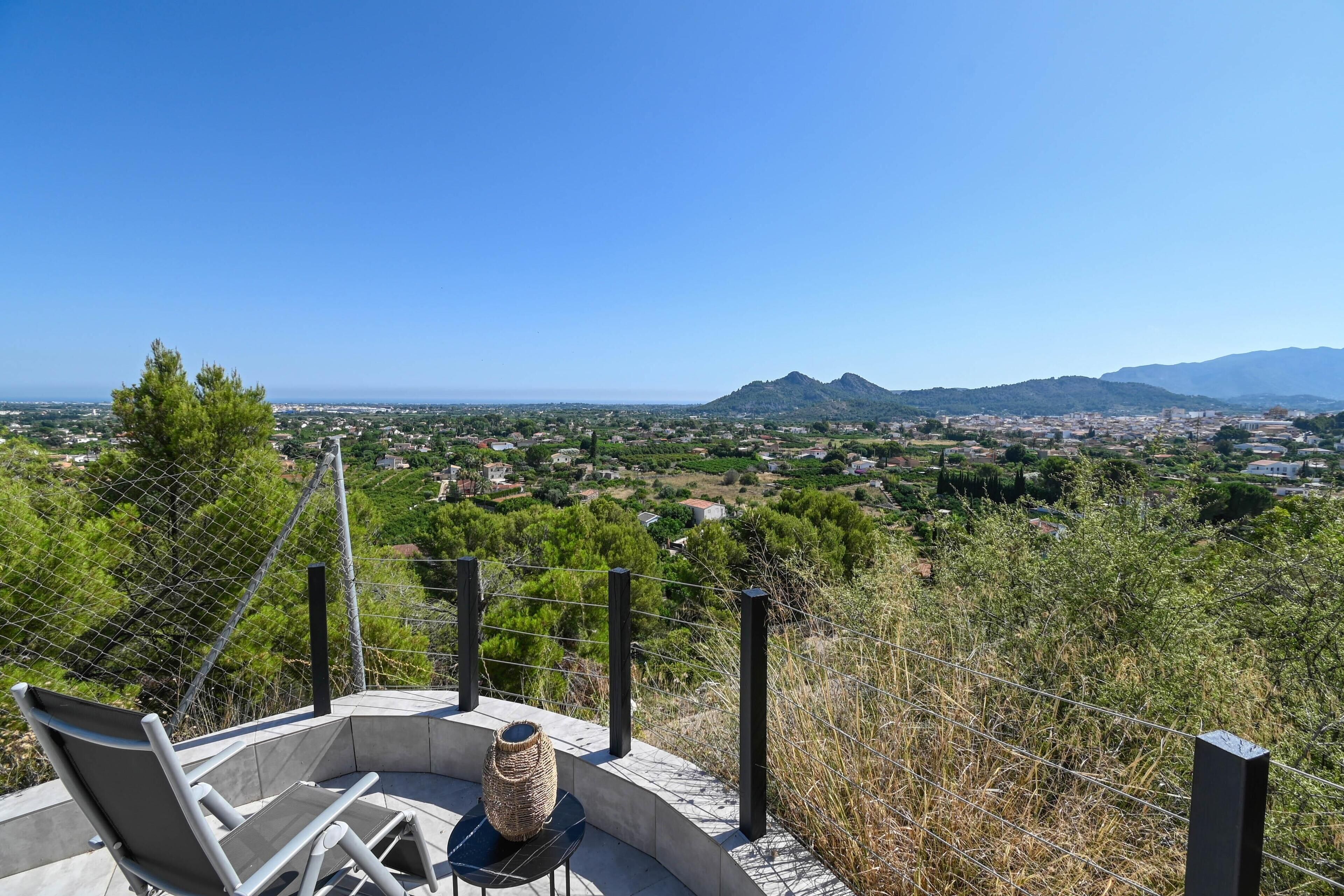 A terrace with a view of a town and mountains.