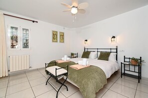 Ein Schlafzimmer mit zwei Betten, einem Deckenventilator, Wandleuchten, einer Heizung und einem fenster mit Vorhängen.