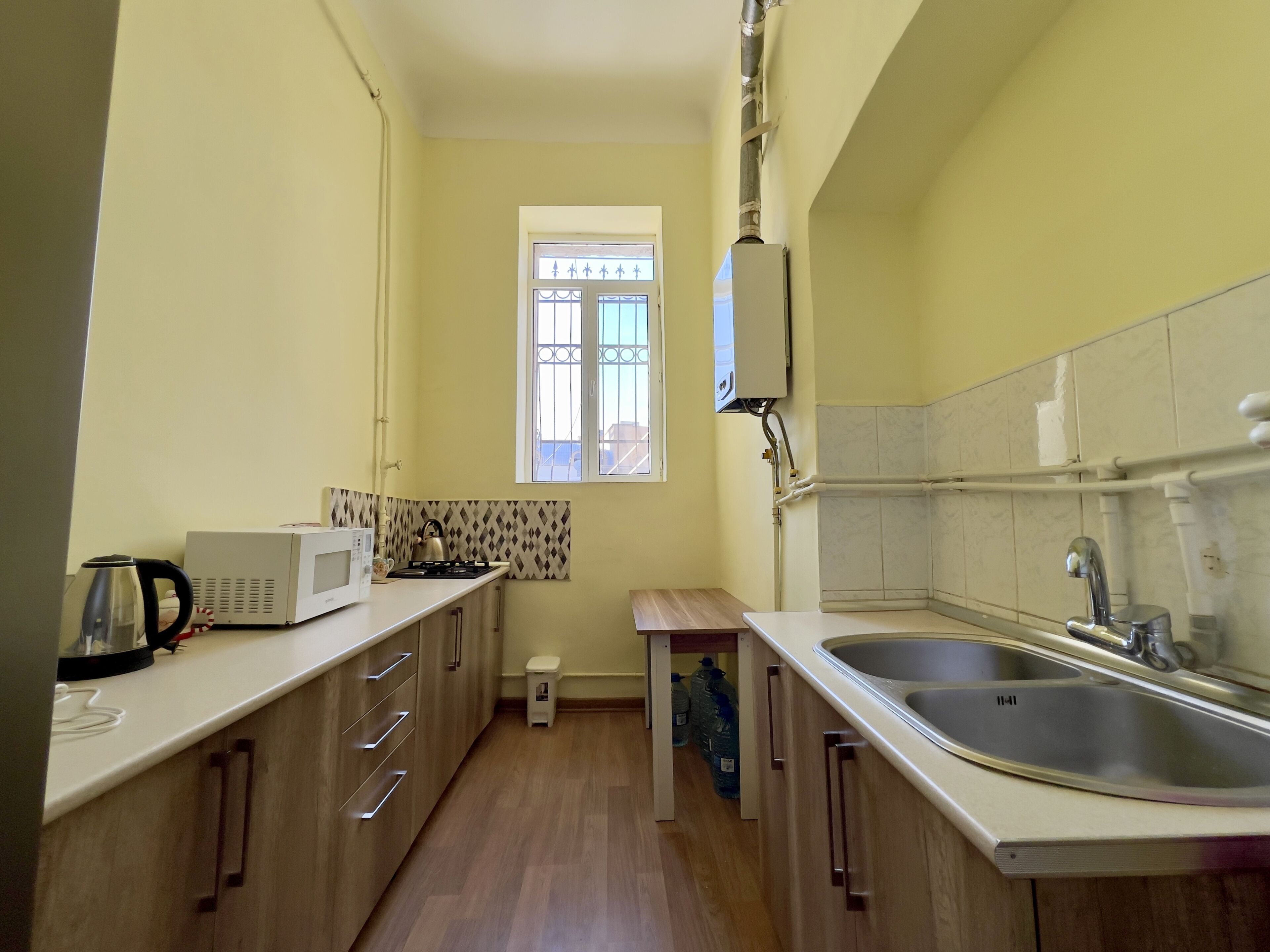 Una cucina compatta con forno a microonde, bollitore e lavandino.