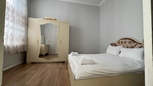 A bedroom with a bed, a wardrobe, and a mirror.