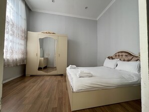 A bedroom with a bed, a wardrobe, and a mirror.
