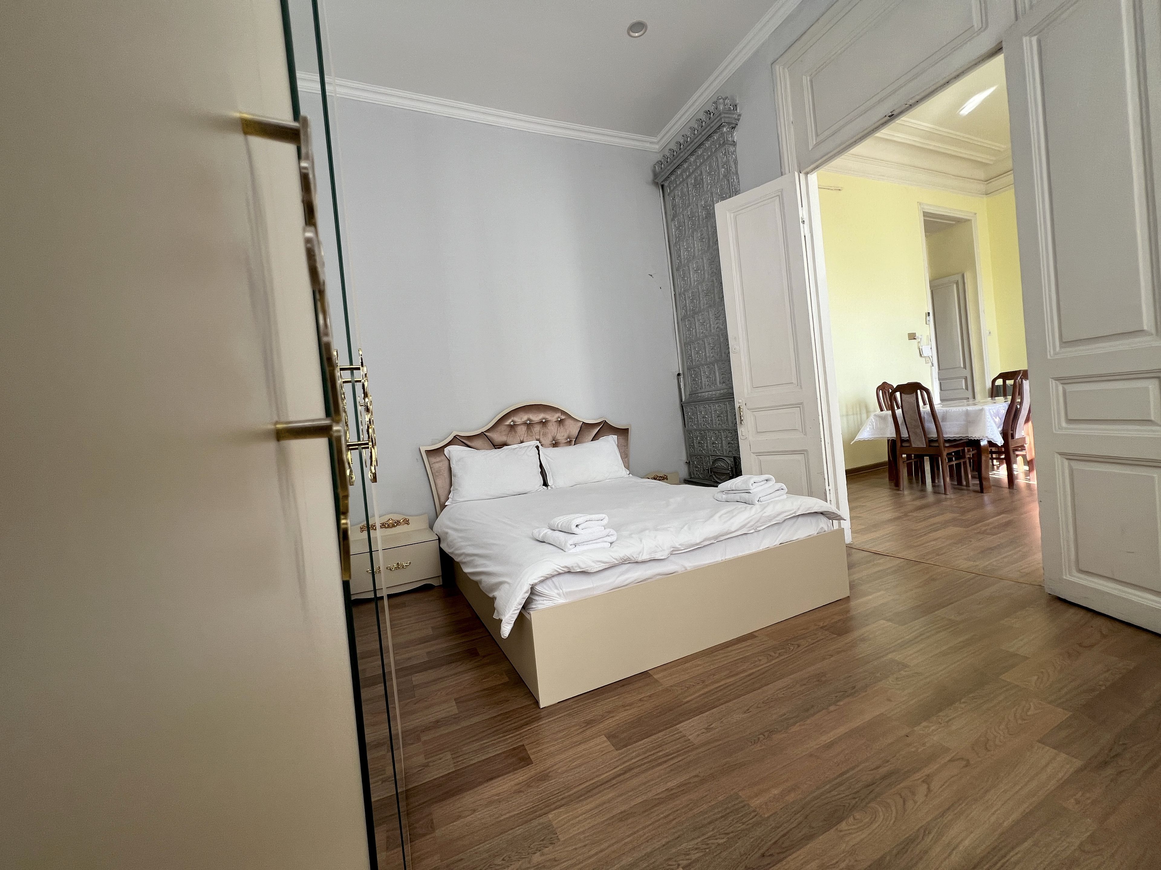 A bedroom with a bed, bedside tables, a wardrobe, and a dining area with chairs and a table.