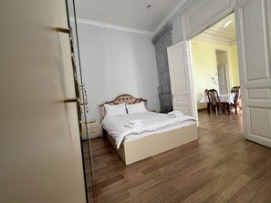 A bedroom with a bed, bedside tables, a wardrobe, and a dining area with chairs and a table.