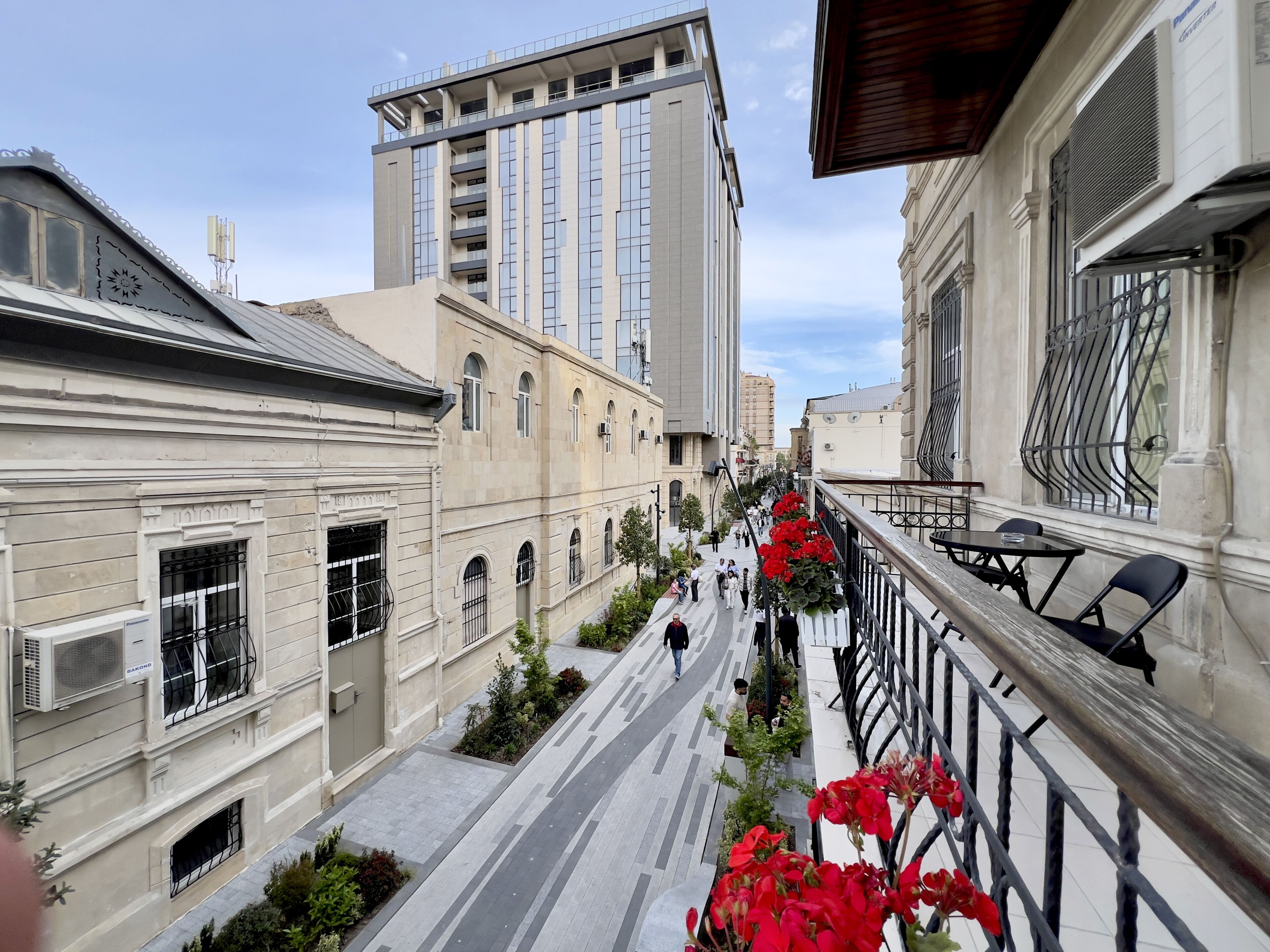 A narrow street flanked by buildings with balconies and a pedestrian walkway.