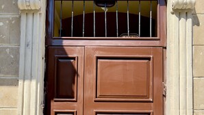 A brown double door with a metal bar above it, set in a building with stone walls.