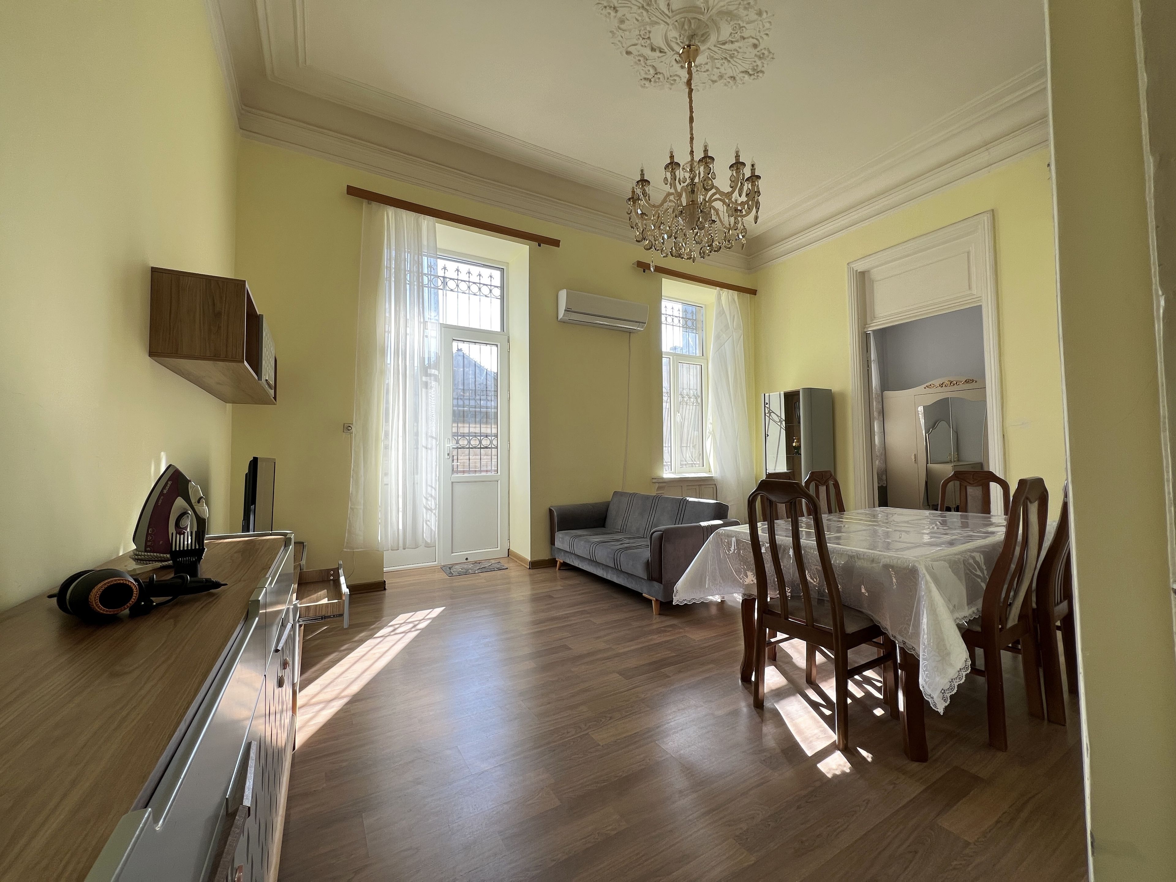 Amplia sala de estar con mesa de comedor, sofá y una lámpara de araña.