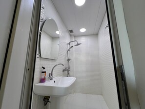 A bathroom with a white sink, mirror, and shower.