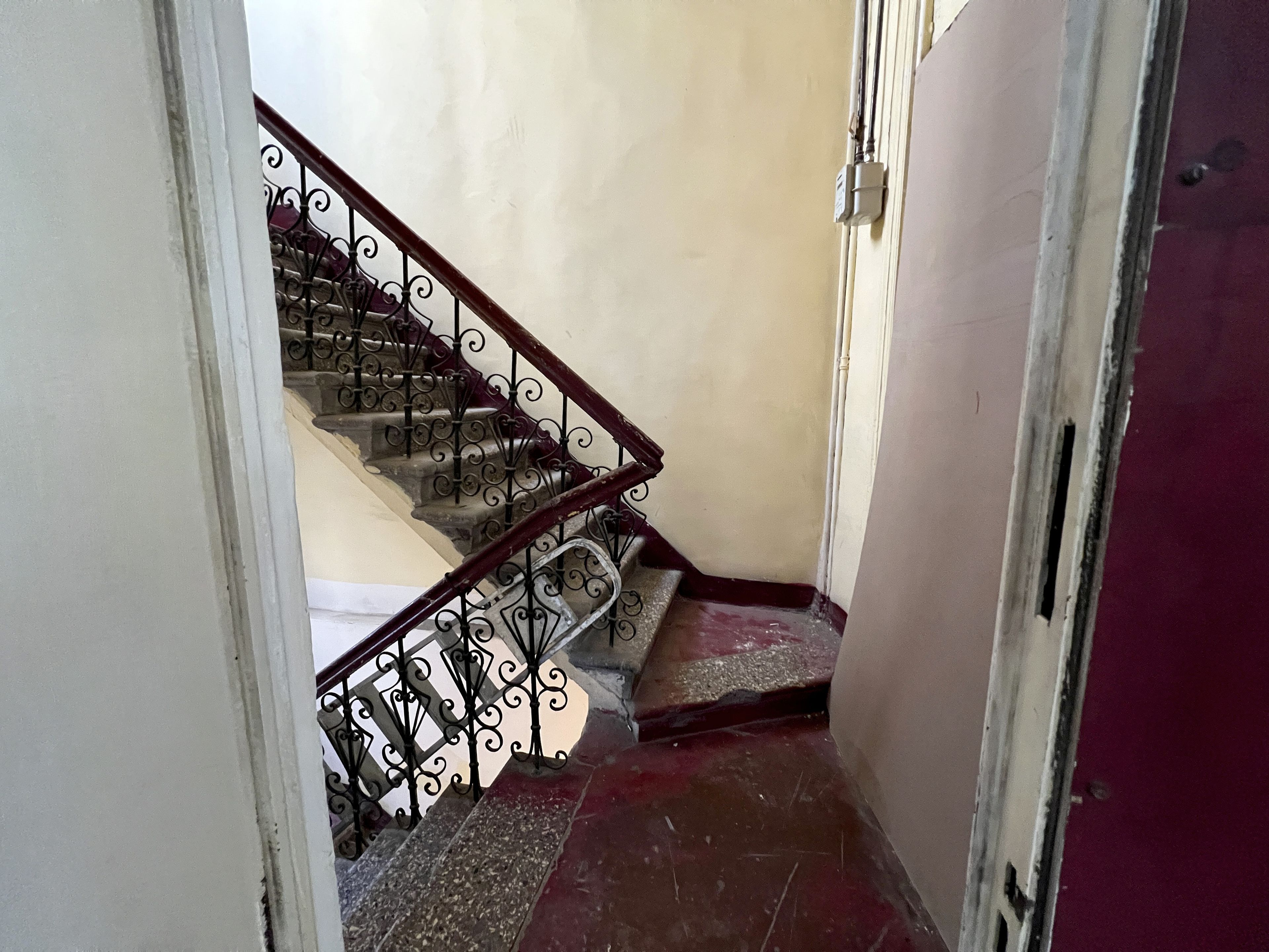 A staircase with ornate metal railings and a red-tiled floor.